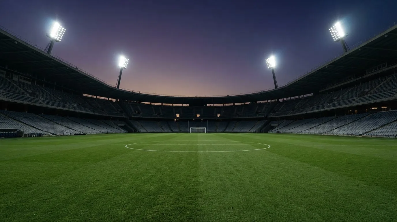 An empty football stadium with floodlight masts at dusk