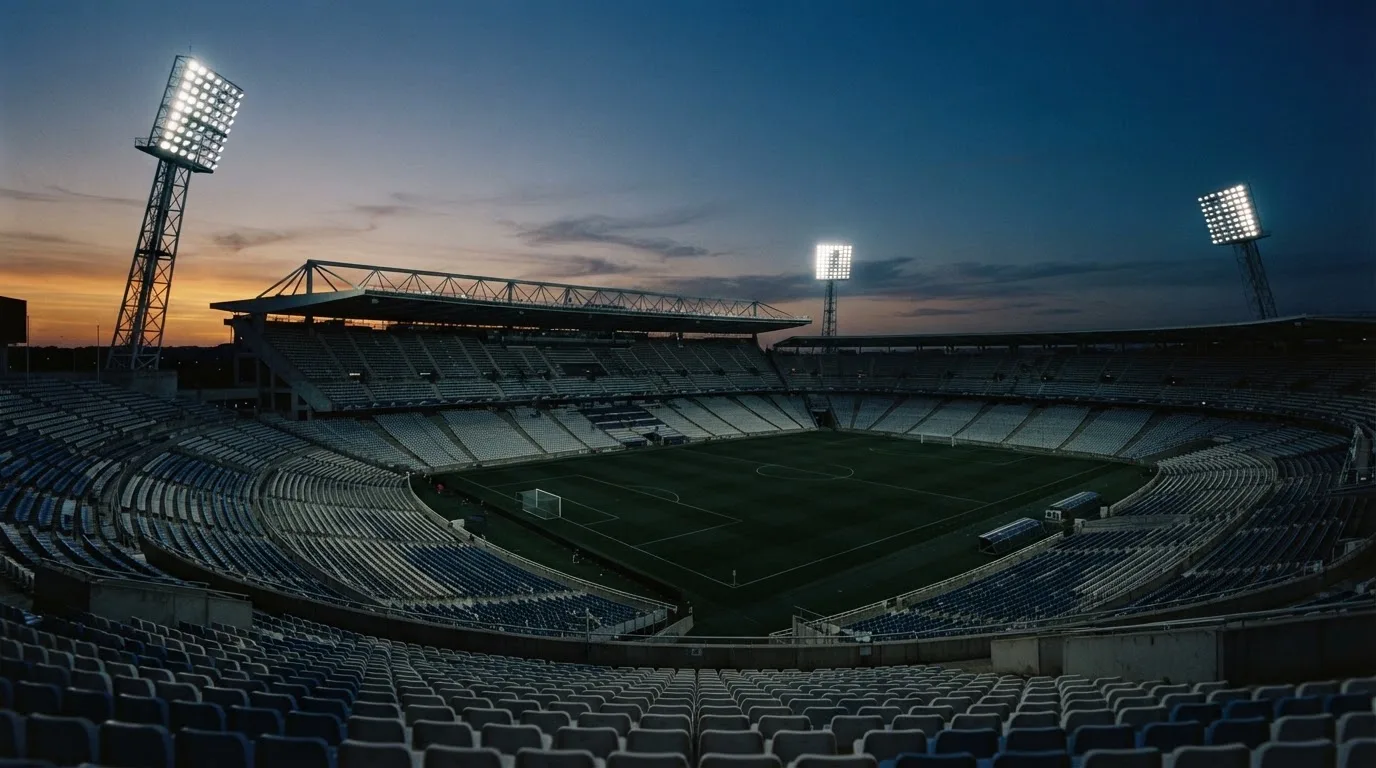 An empty football stadium with floodlight masts at dusk