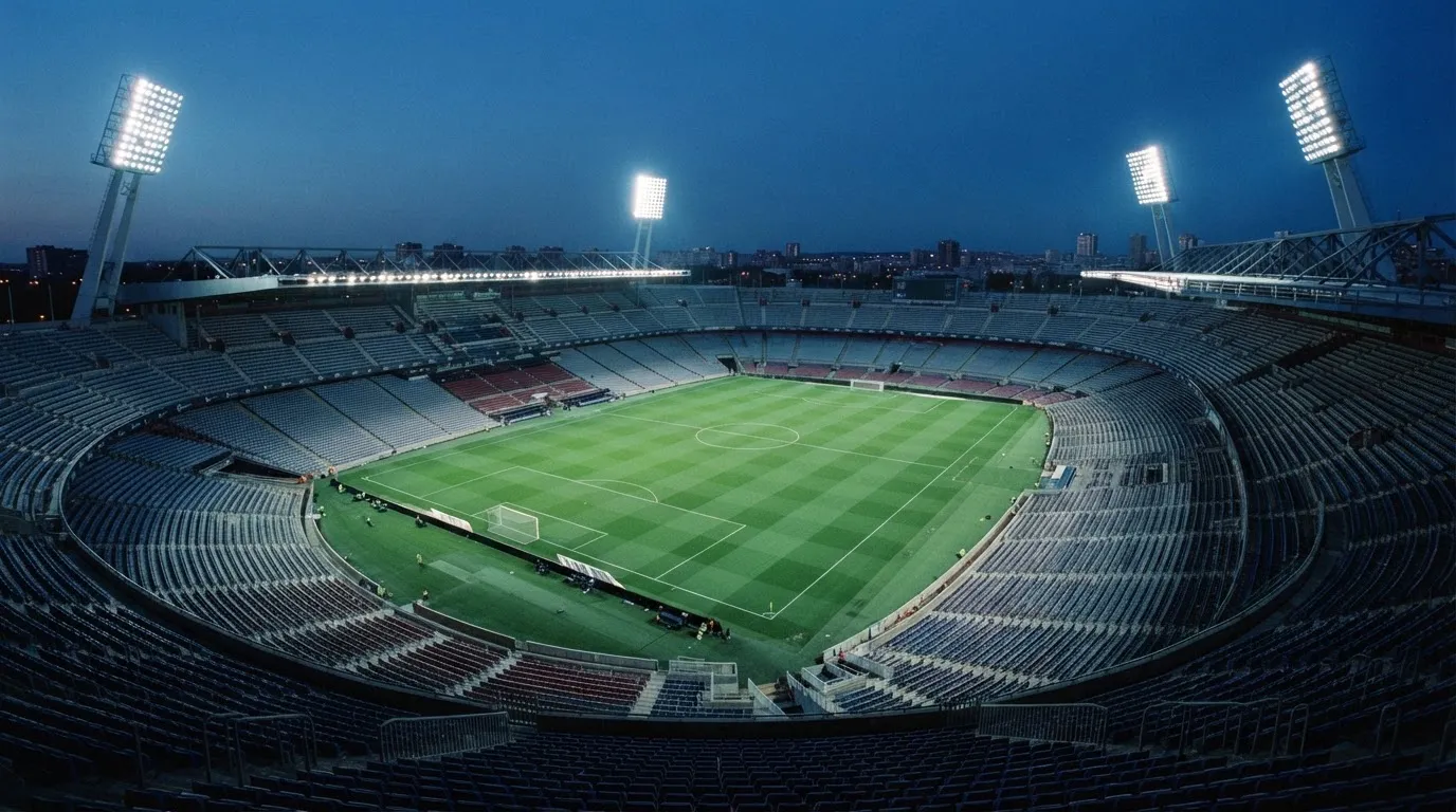 An empty football stadium with floodlight masts at dusk