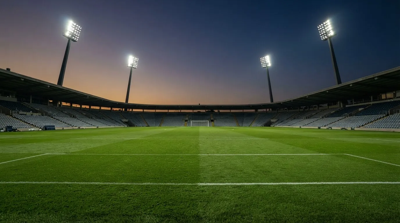 An empty football stadium with floodlight masts at dusk