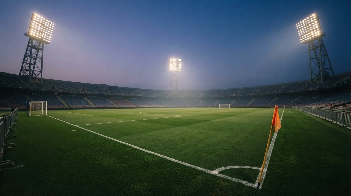 An empty football stadium with floodlight masts at dusk