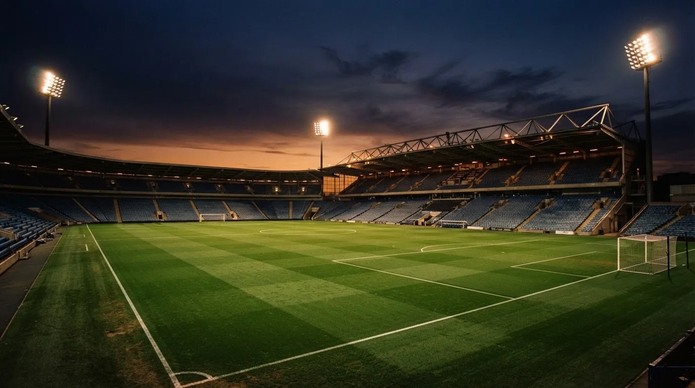 An empty football stadium with floodlight masts at dusk
