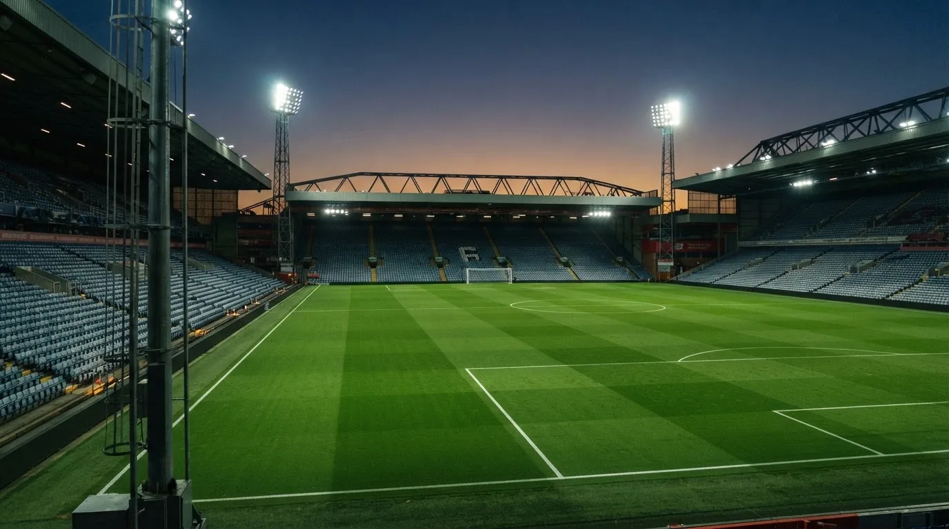 An empty football stadium with floodlight masts at dusk