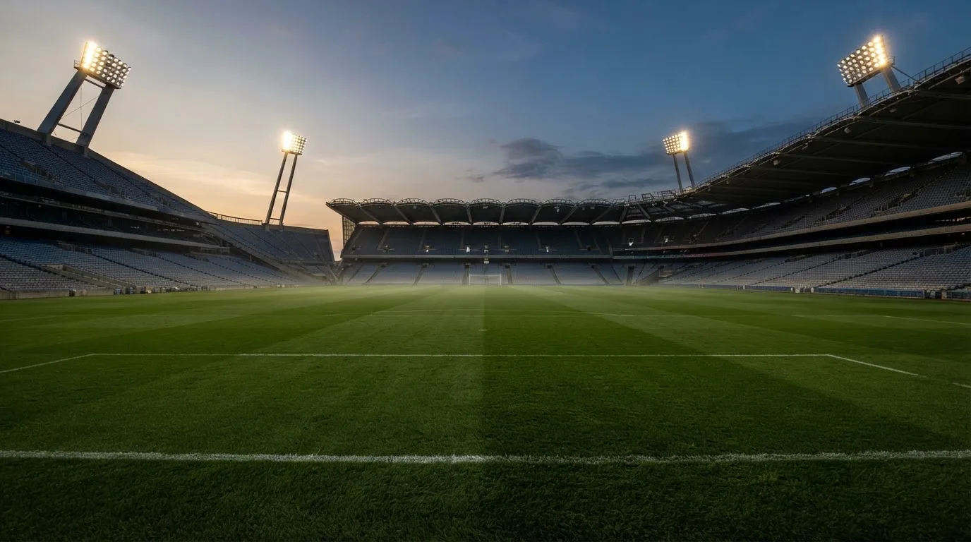 An empty football stadium with floodlight masts at dusk