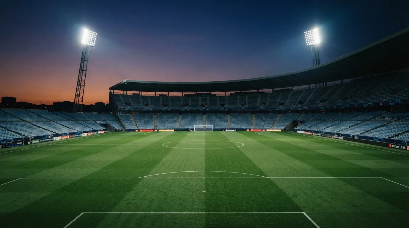 An empty football stadium with floodlight masts at dusk