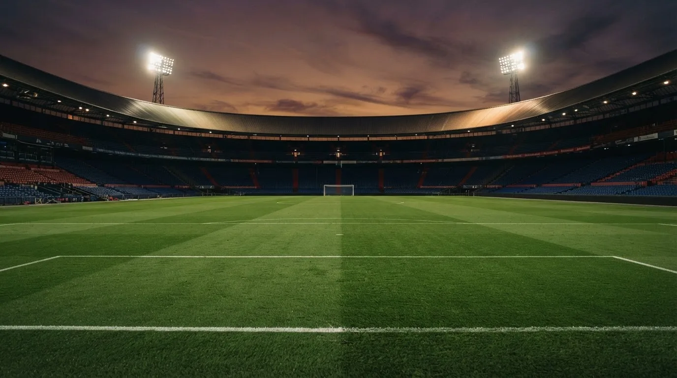 An empty football stadium with floodlight masts at dusk
