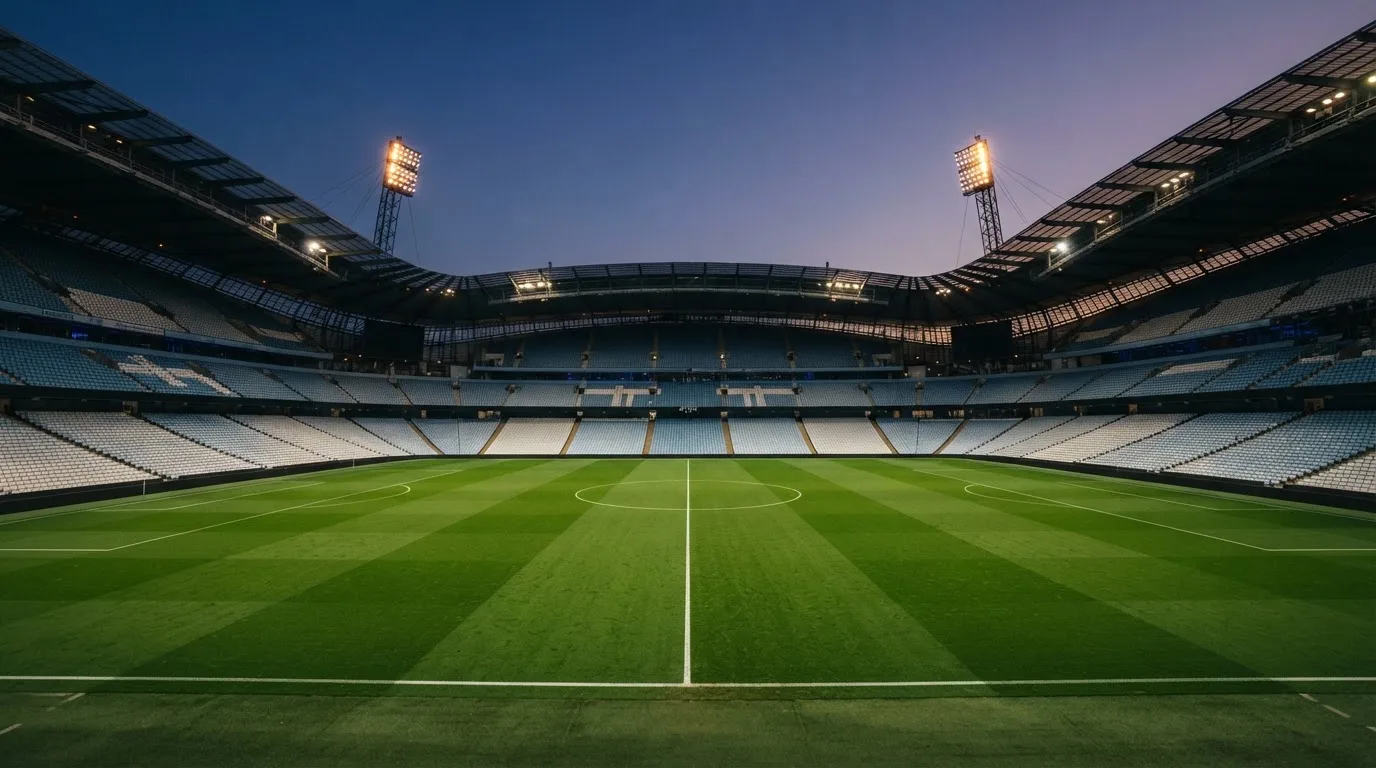 An empty football stadium with floodlight masts at dusk