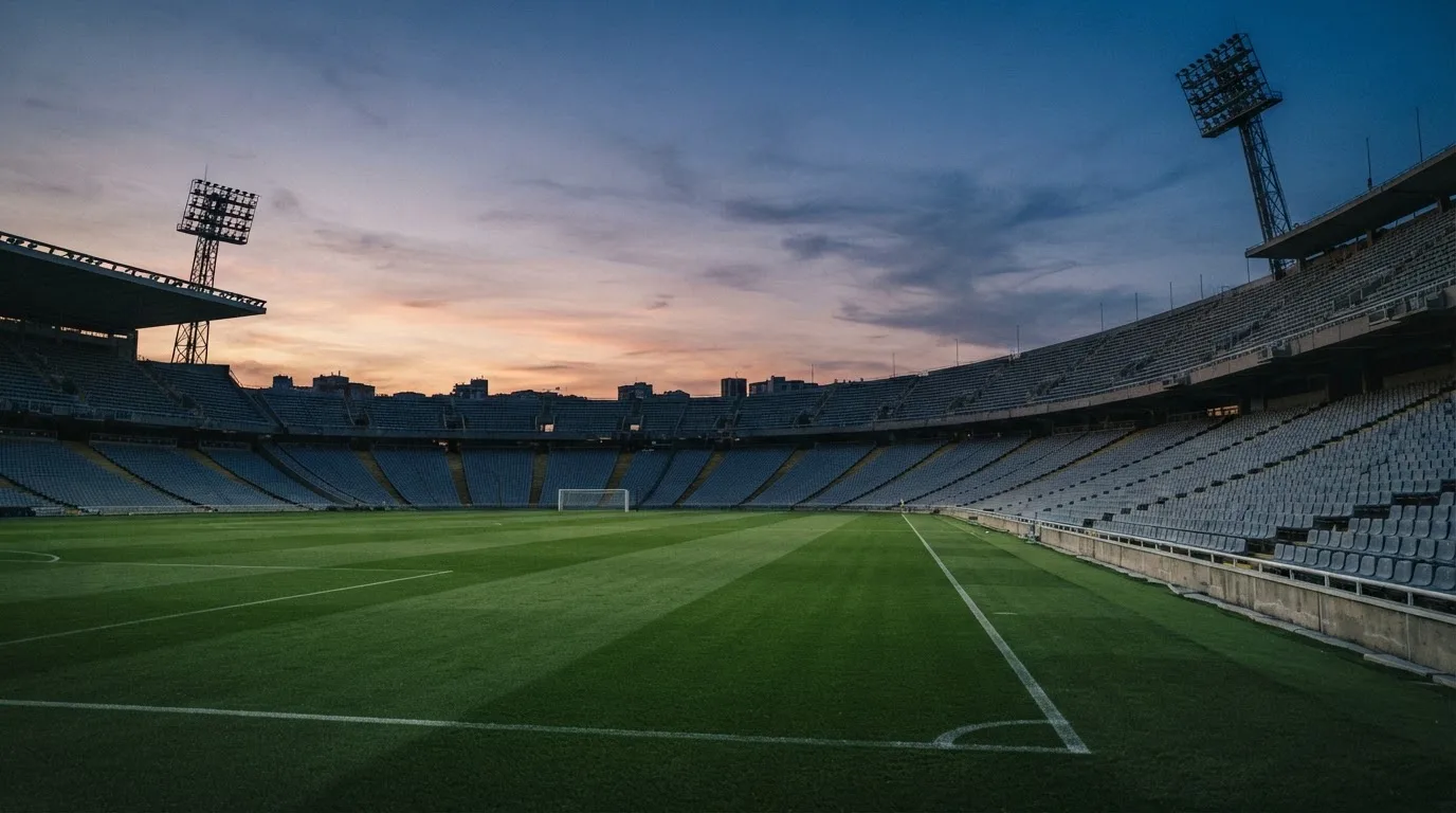 An empty football stadium with floodlight masts at dusk