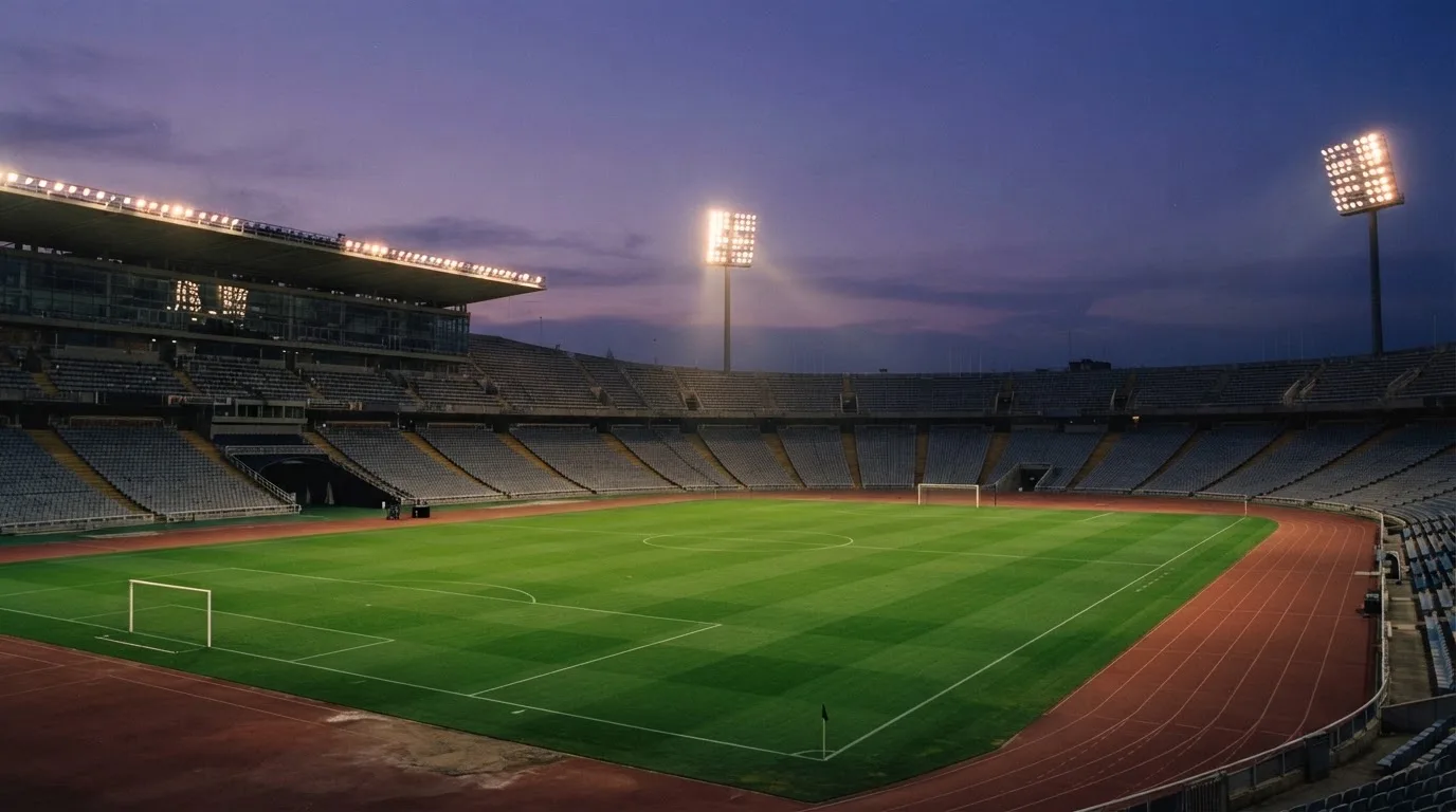 An empty football stadium with floodlight masts at dusk