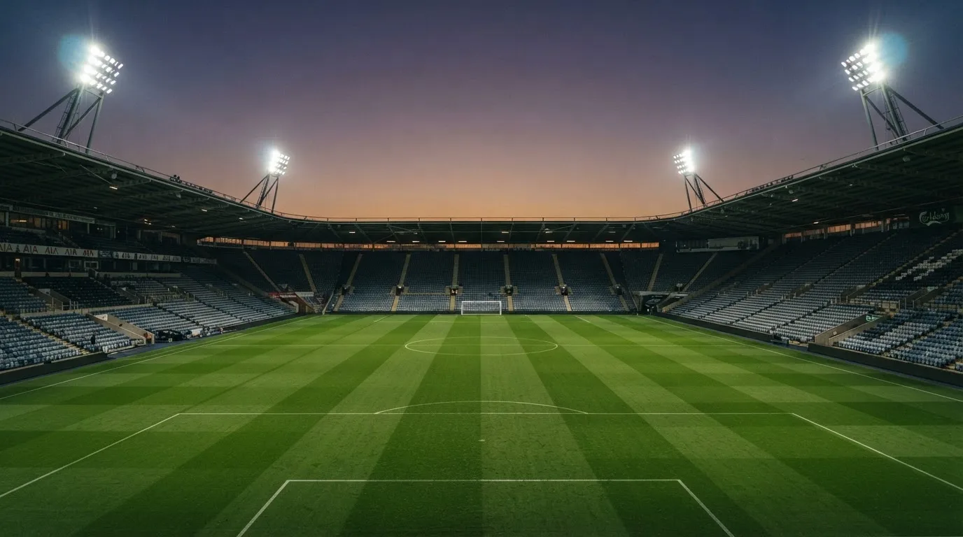 An empty football stadium with floodlight masts at dusk