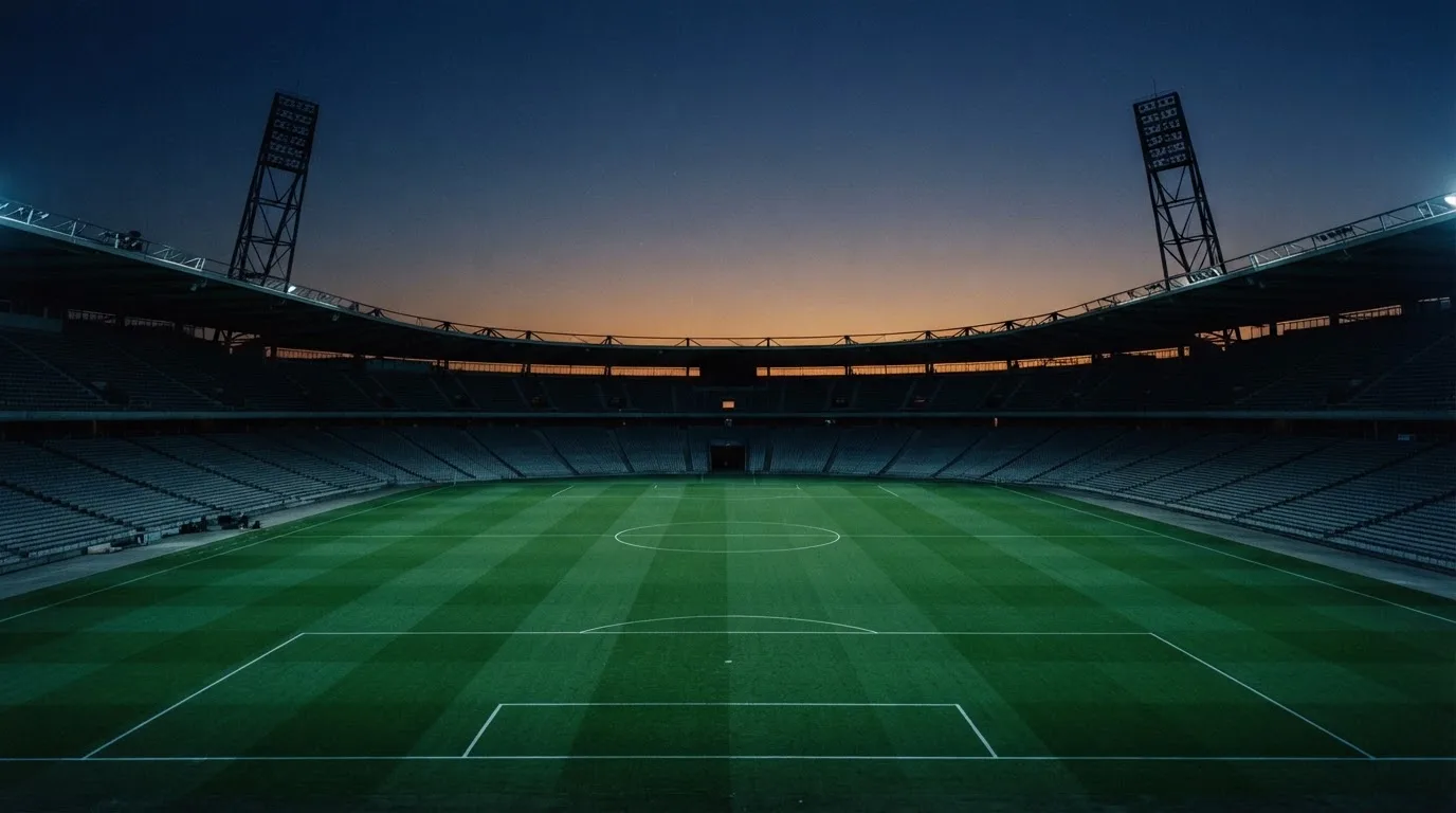 An empty football stadium with floodlight masts at dusk