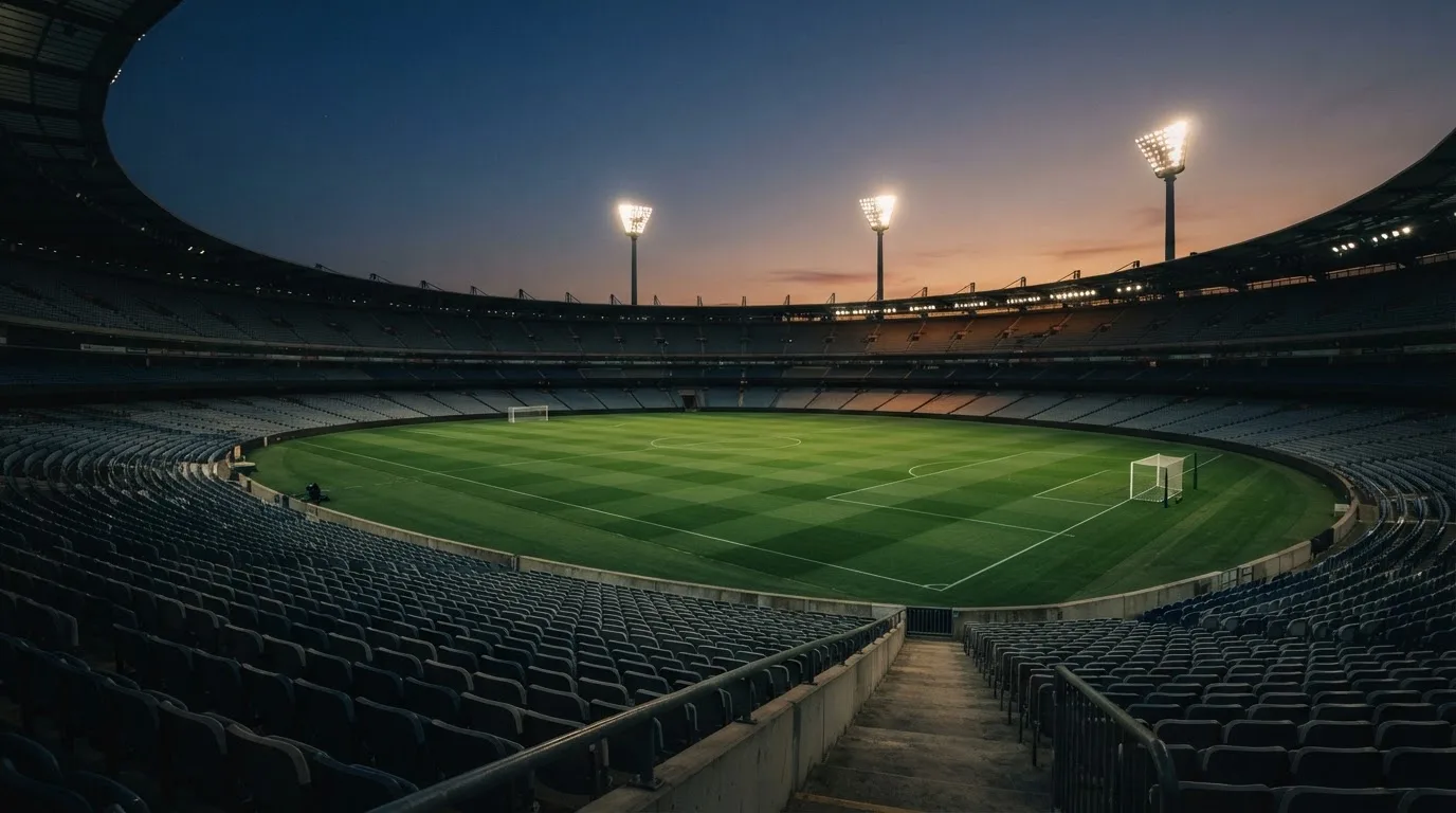 An empty football stadium with floodlight masts at dusk