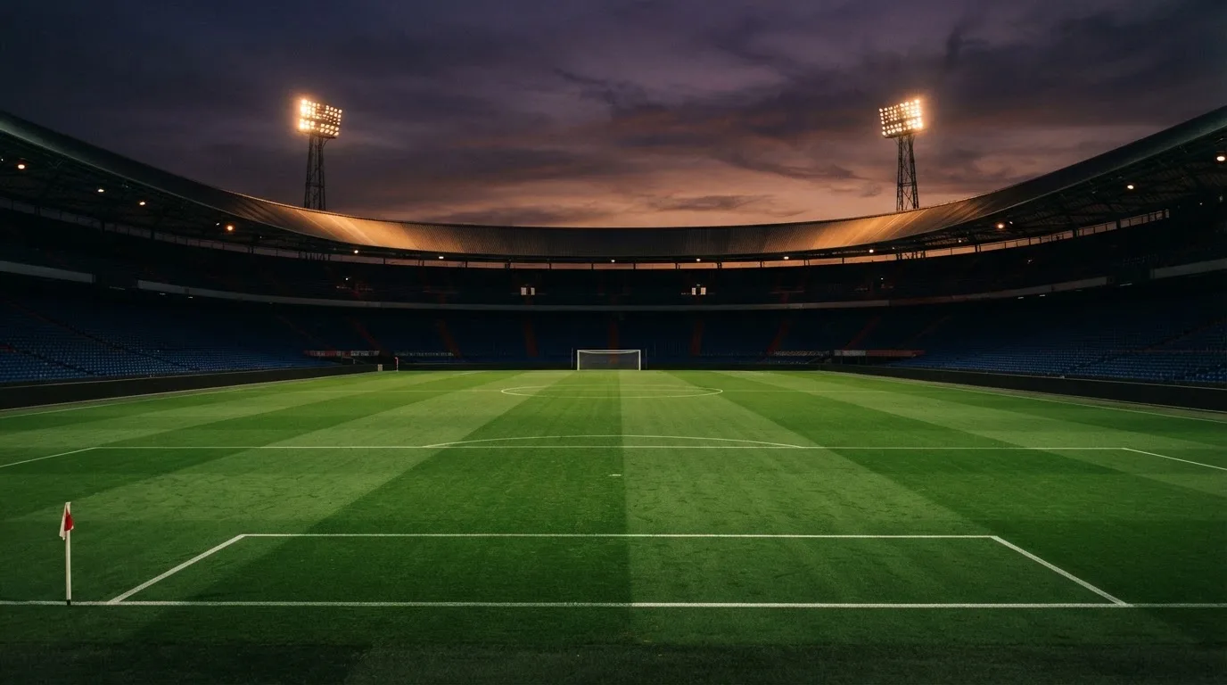 An empty football stadium with floodlight masts at dusk