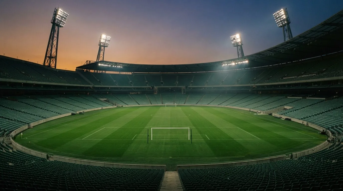 An empty football stadium with floodlight masts at dusk