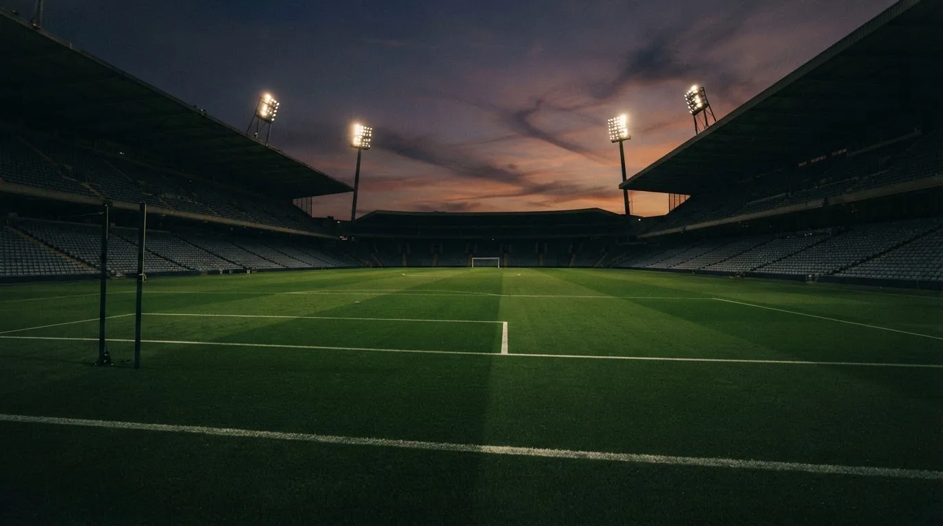 An empty football stadium with floodlight masts at dusk