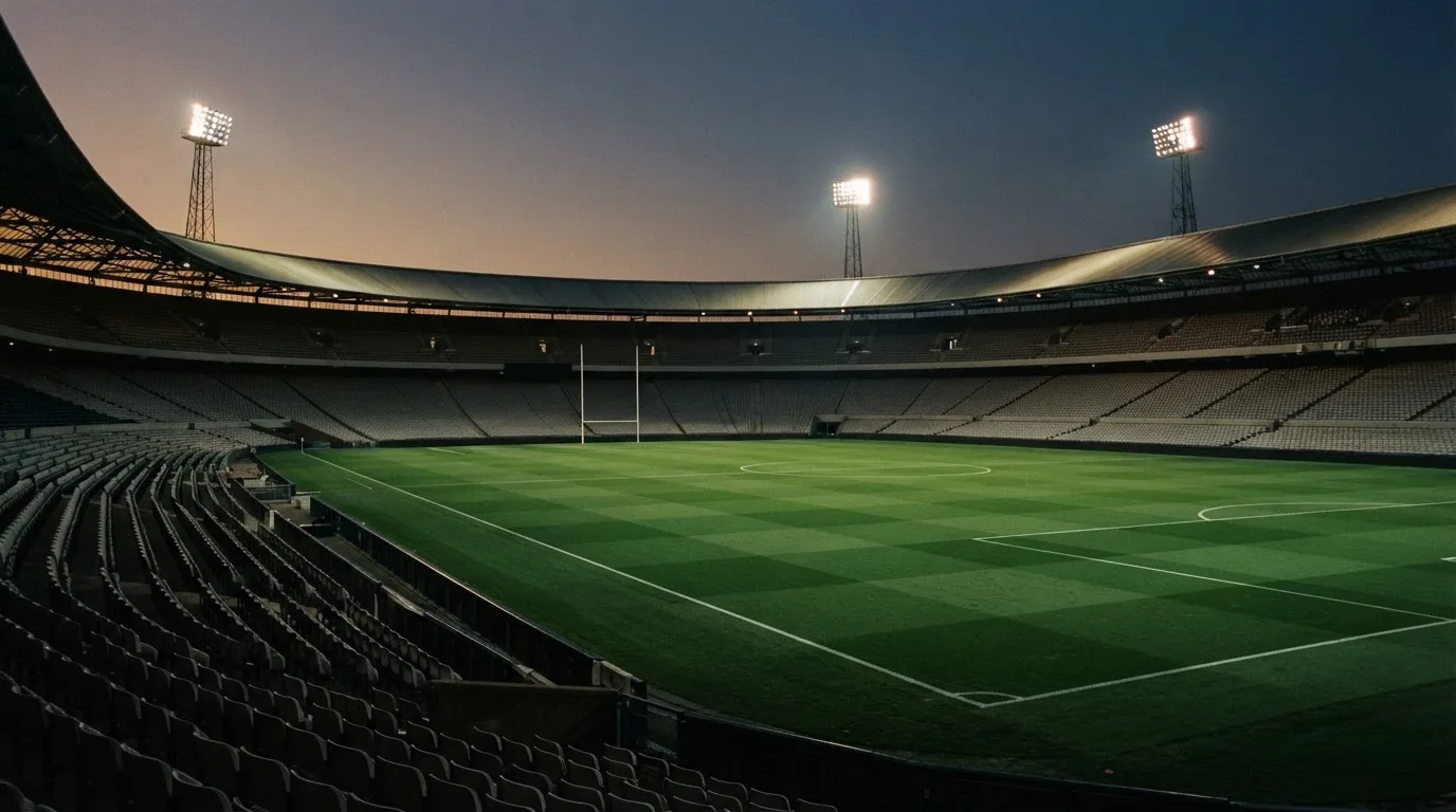 An empty football stadium with floodlight masts at dusk