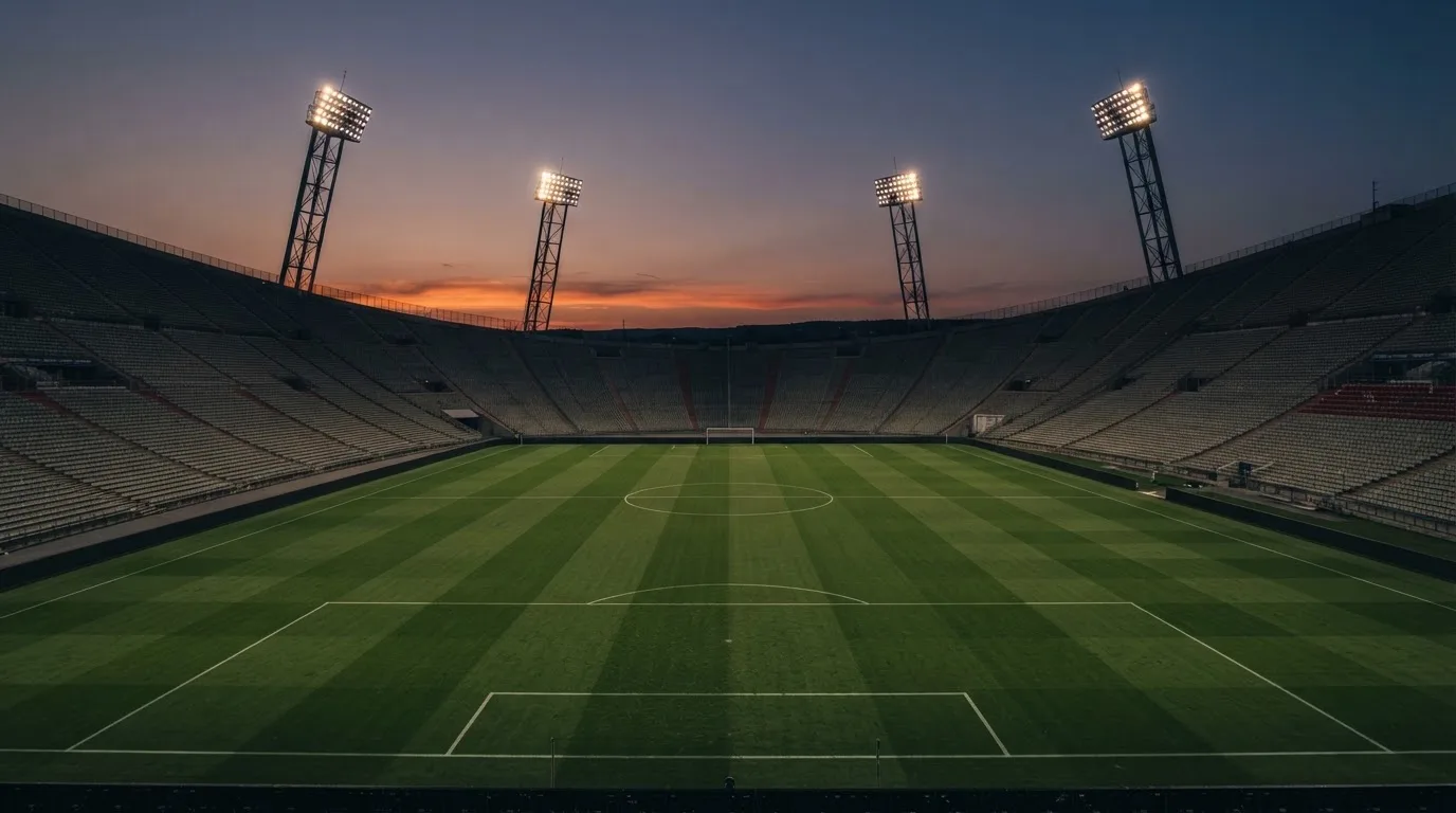 An empty football stadium with floodlight masts at dusk