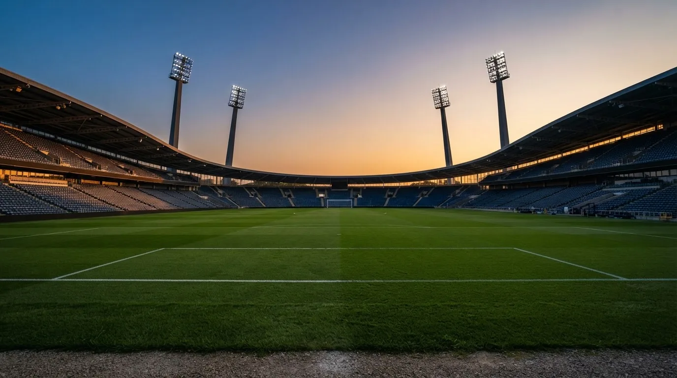 An empty football stadium with floodlight masts at dusk