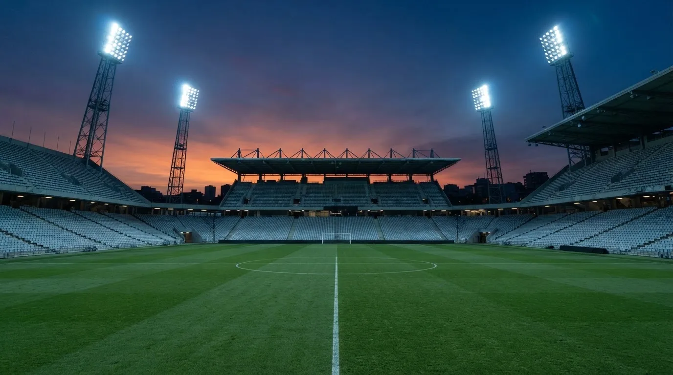 An empty football stadium with floodlight masts at dusk
