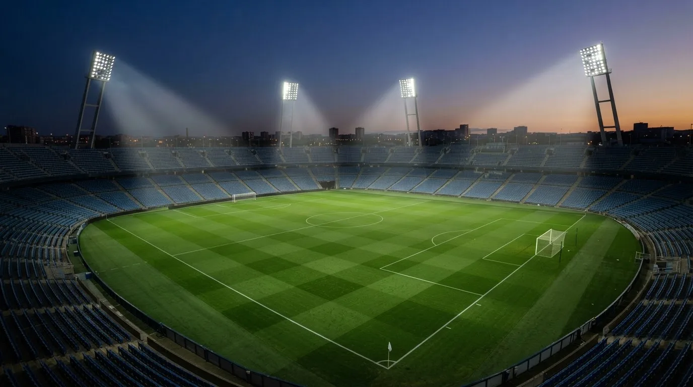 An empty football stadium with floodlight masts at dusk