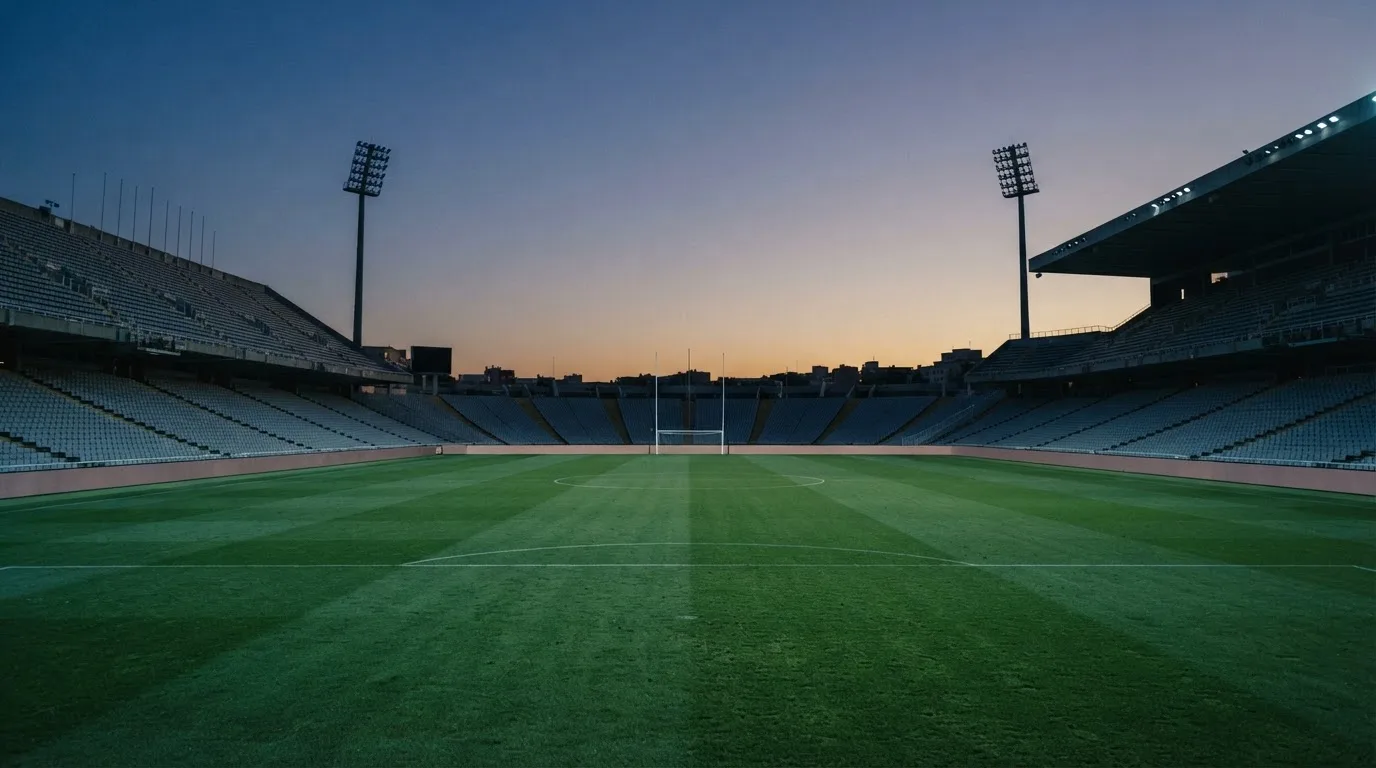 An empty football stadium with floodlight masts at dusk