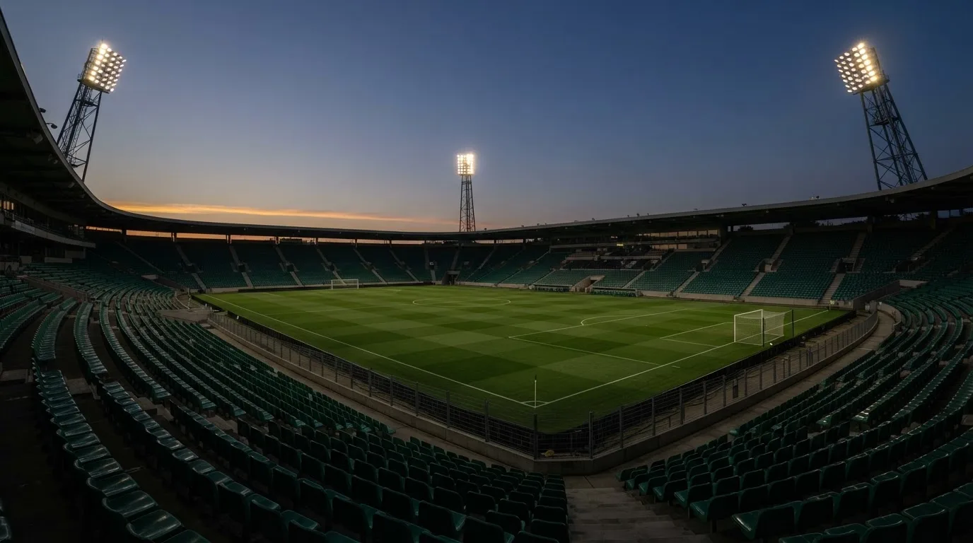 An empty football stadium with floodlight masts at dusk