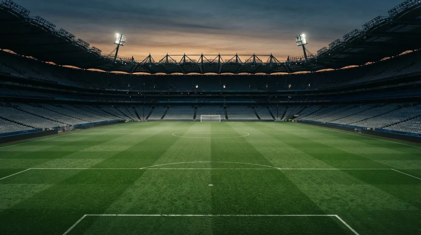 An empty football stadium with floodlight masts at dusk