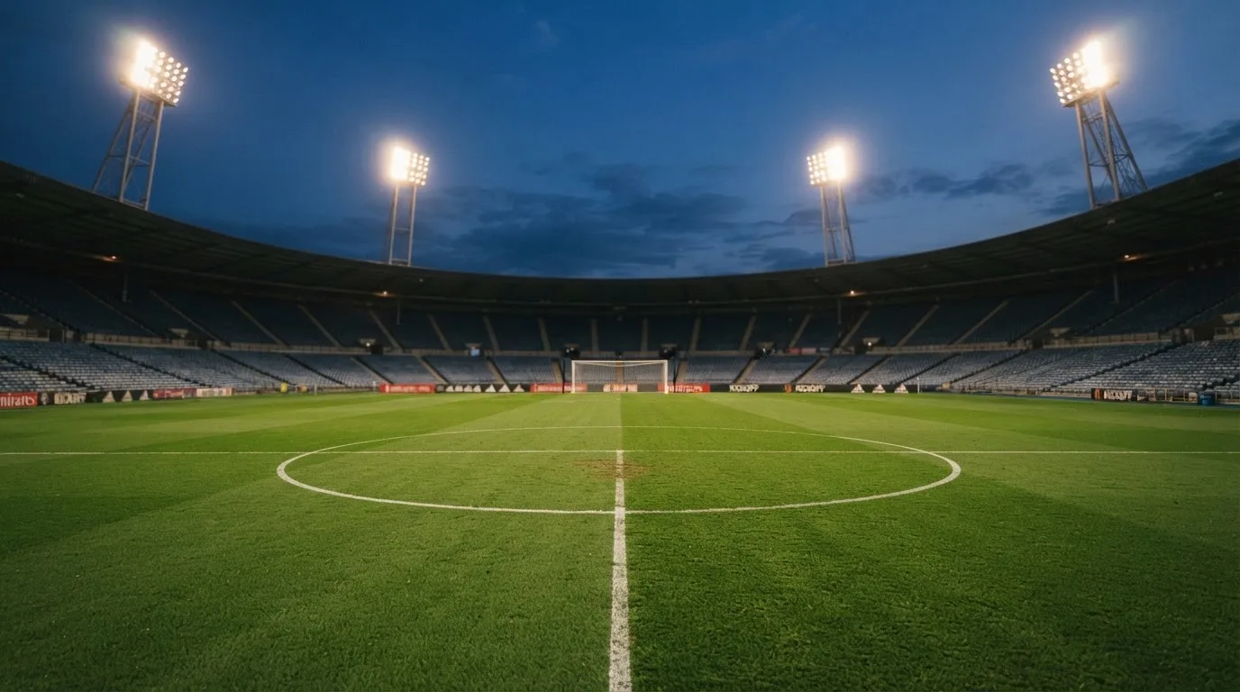 An empty football stadium with floodlight masts at dusk