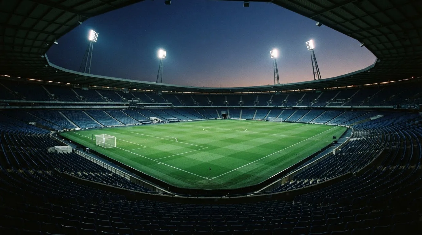 An empty football stadium with floodlight masts at dusk