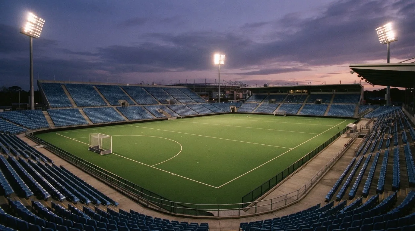 An empty football stadium with floodlight masts at dusk
