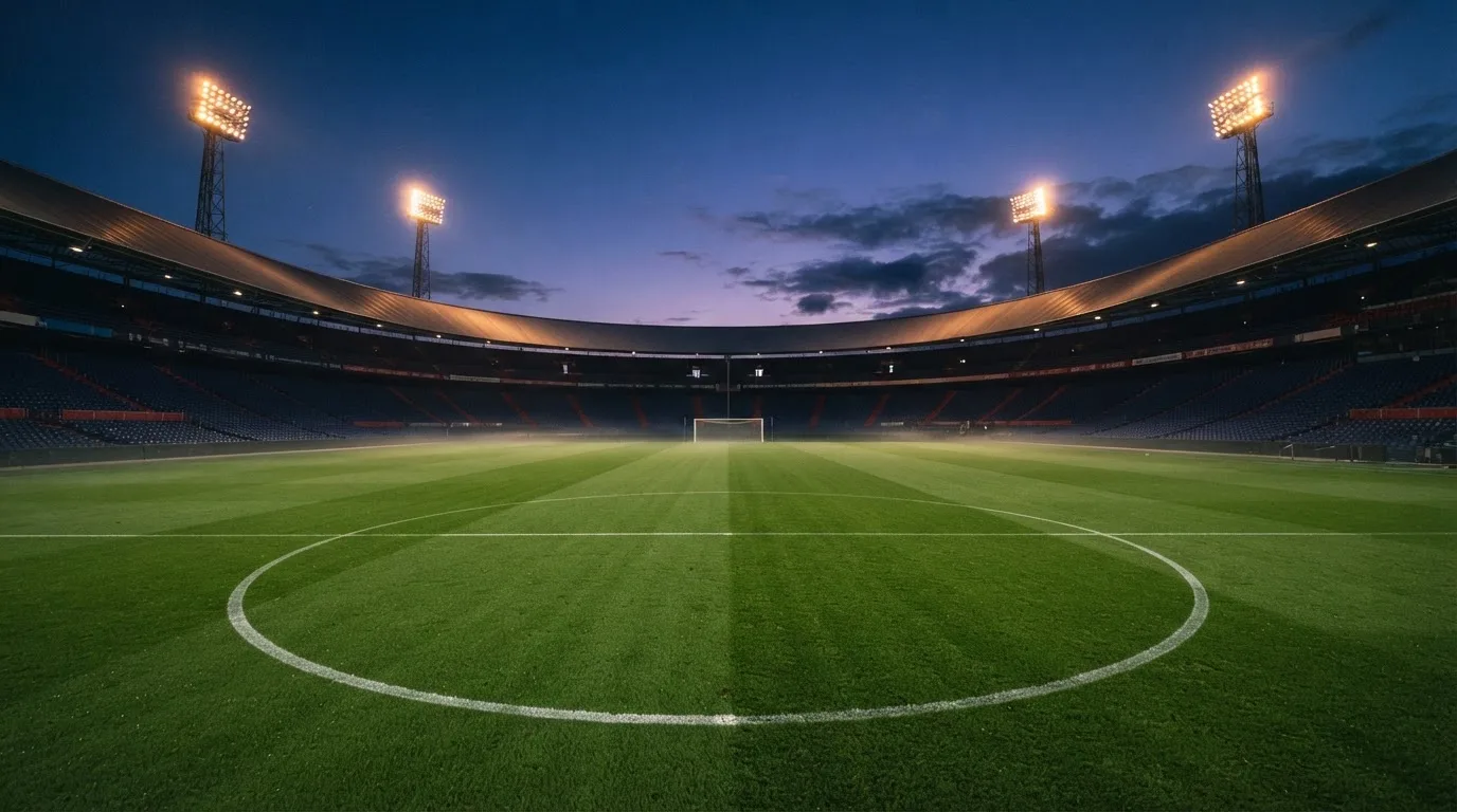 An empty football stadium with floodlight masts at dusk