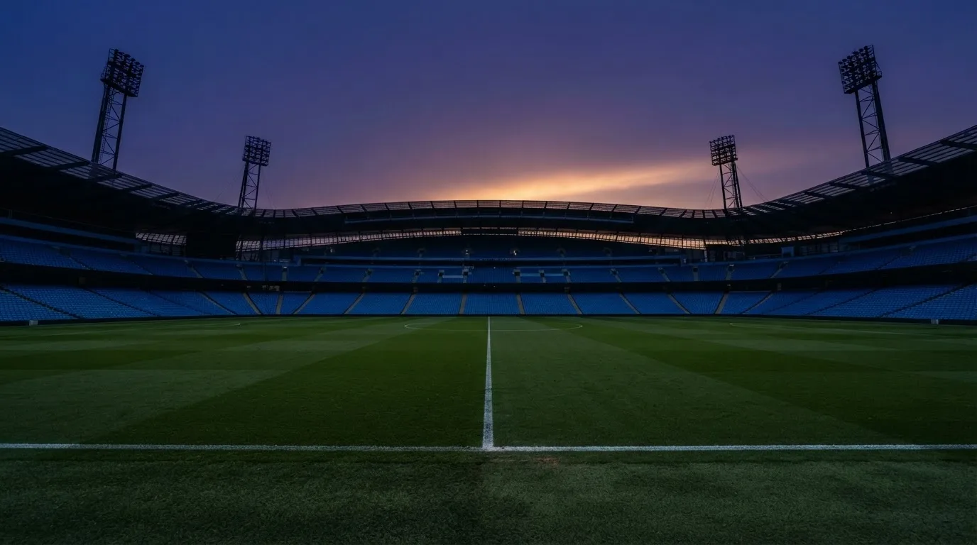 An empty football stadium with floodlight masts at dusk