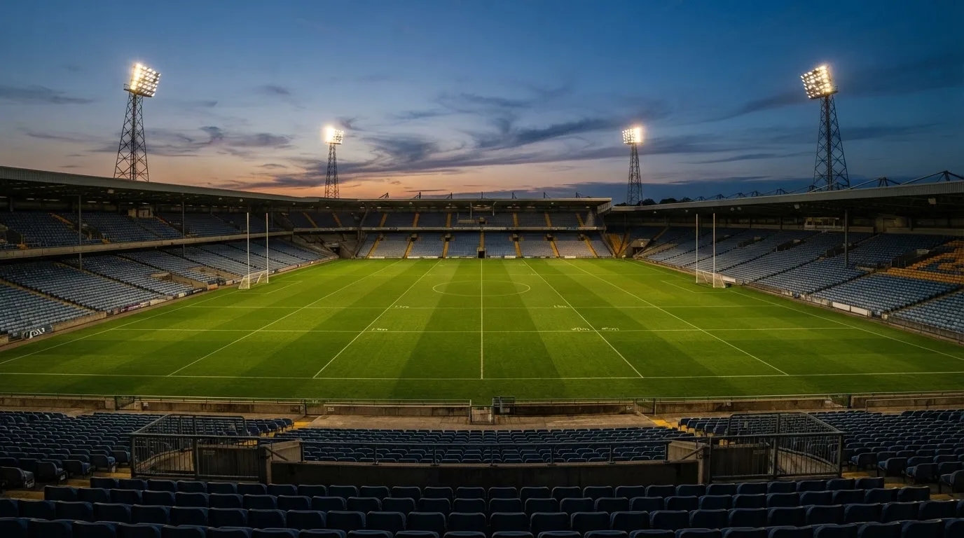 An empty football stadium with floodlight masts at dusk
