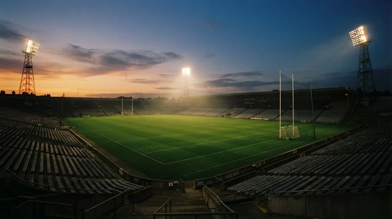 An empty football stadium with floodlight masts at dusk