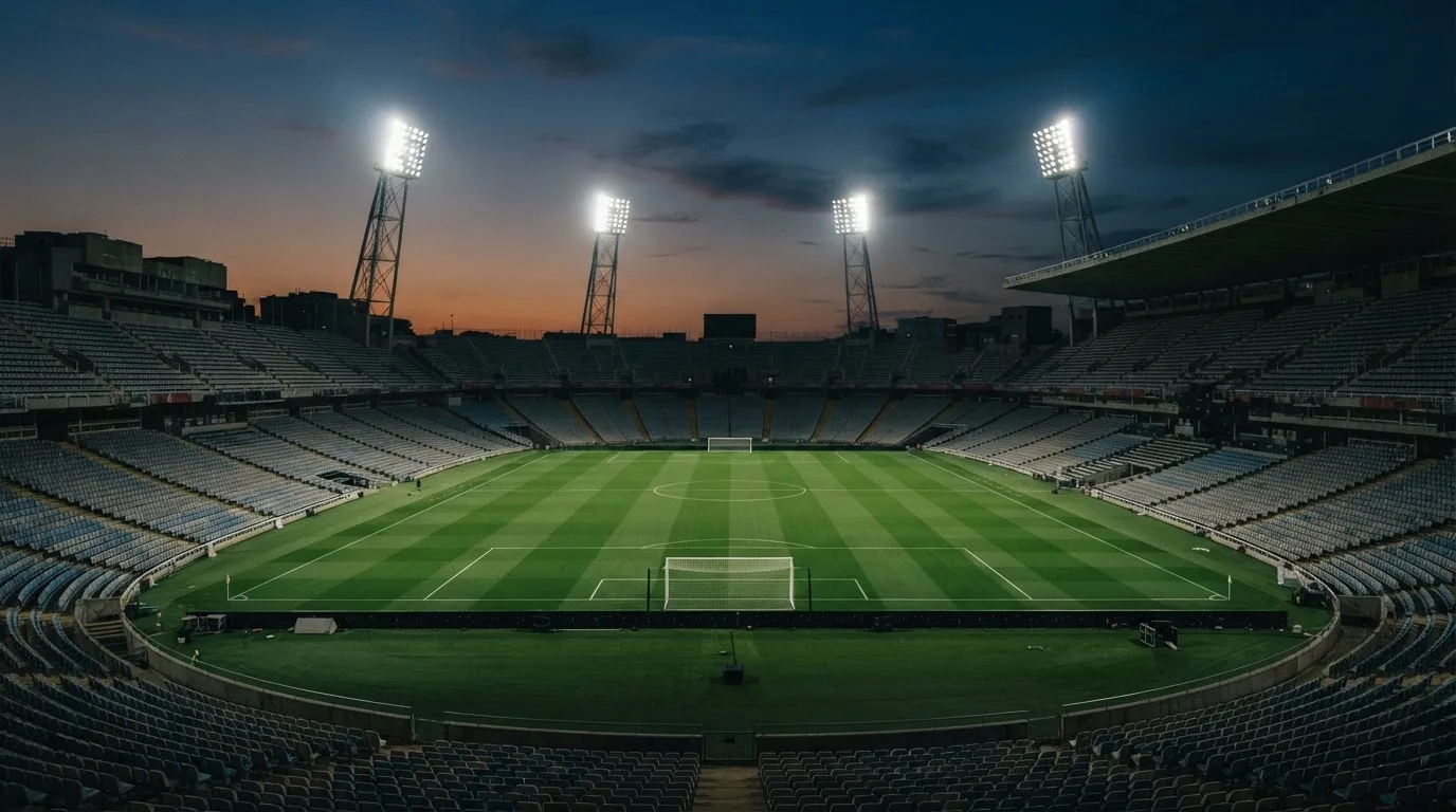 An empty football stadium with floodlight masts at dusk