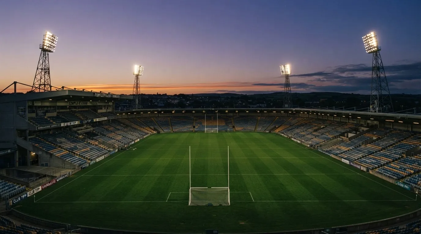 An empty football stadium with floodlight masts at dusk