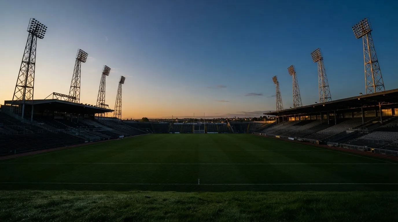 An empty football stadium with floodlight masts at dusk