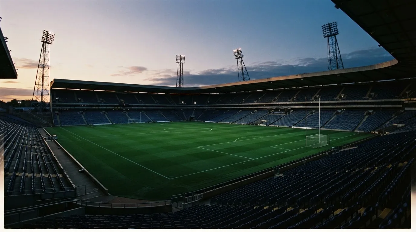 An empty football stadium with floodlight masts at dusk