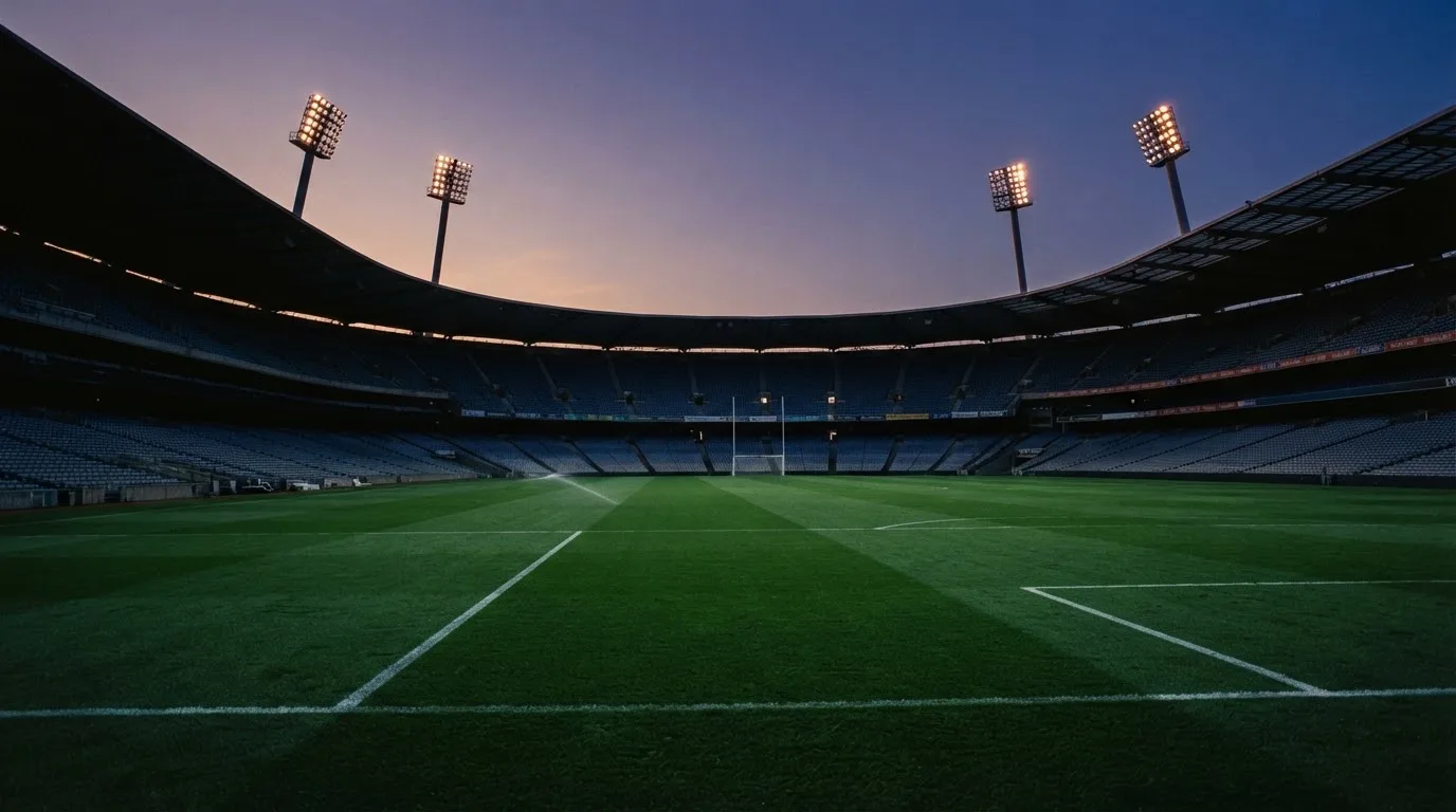 An empty football stadium with floodlight masts at dusk