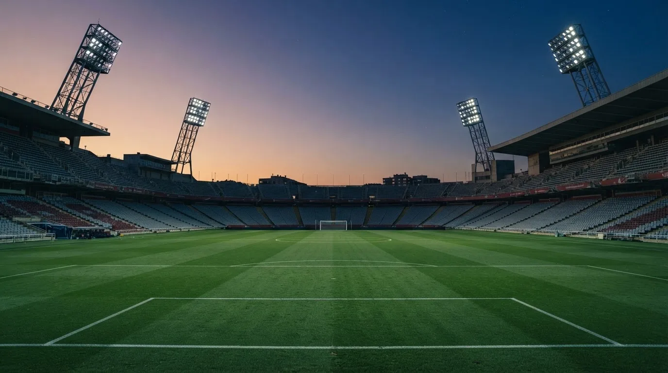 An empty football stadium with floodlight masts at dusk