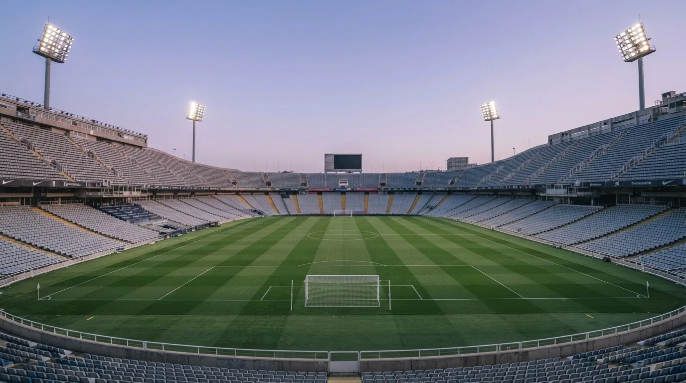 An empty football stadium with floodlight masts at dusk