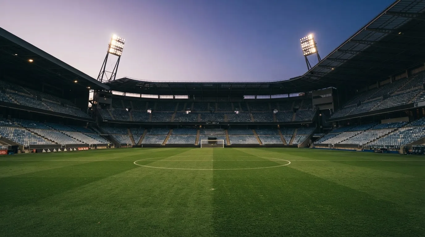 An empty football stadium with floodlight masts at dusk
