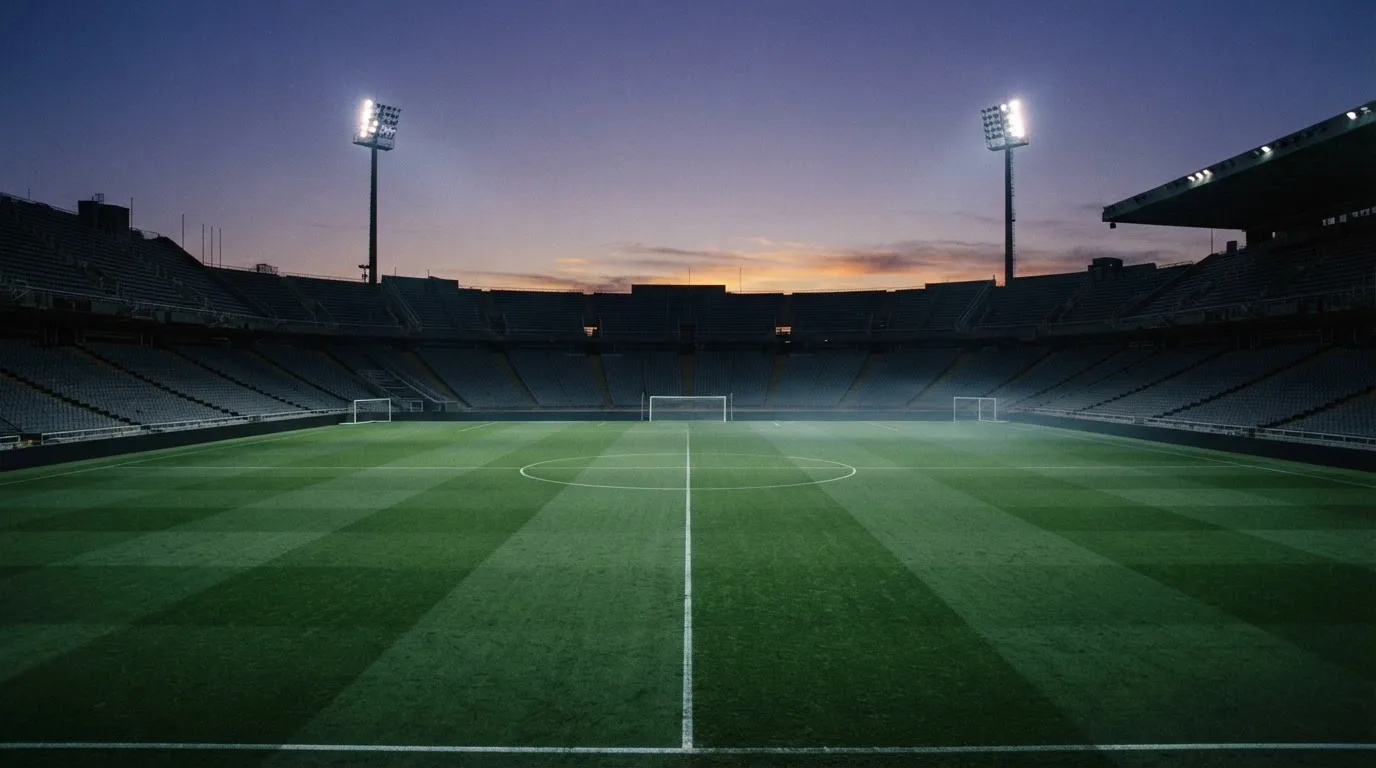 An empty football stadium with floodlight masts at dusk
