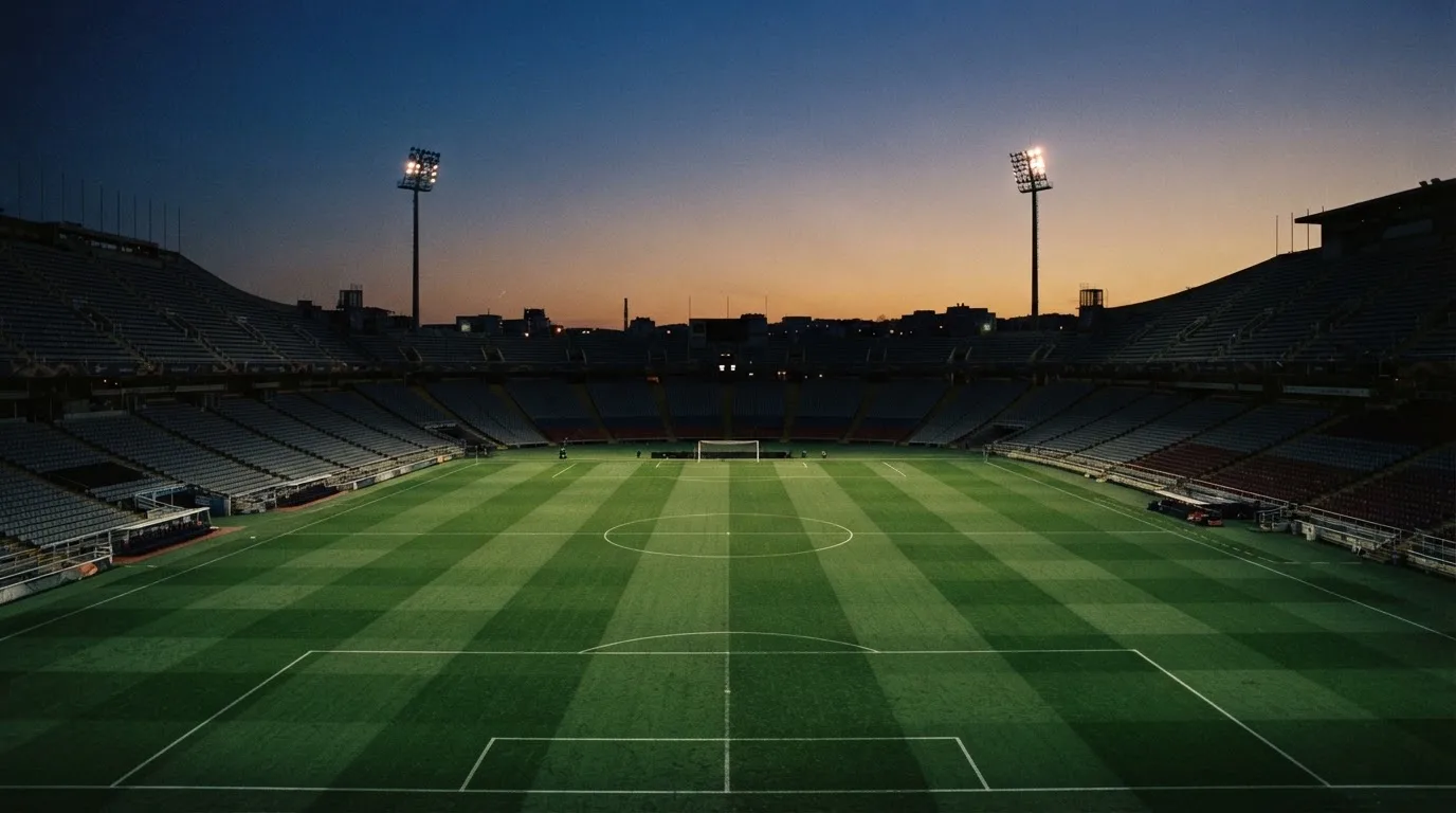 An empty football stadium with floodlight masts at dusk