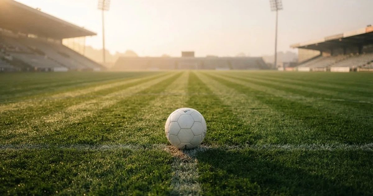 A ball on the centre spot of a grass pitch in morning light