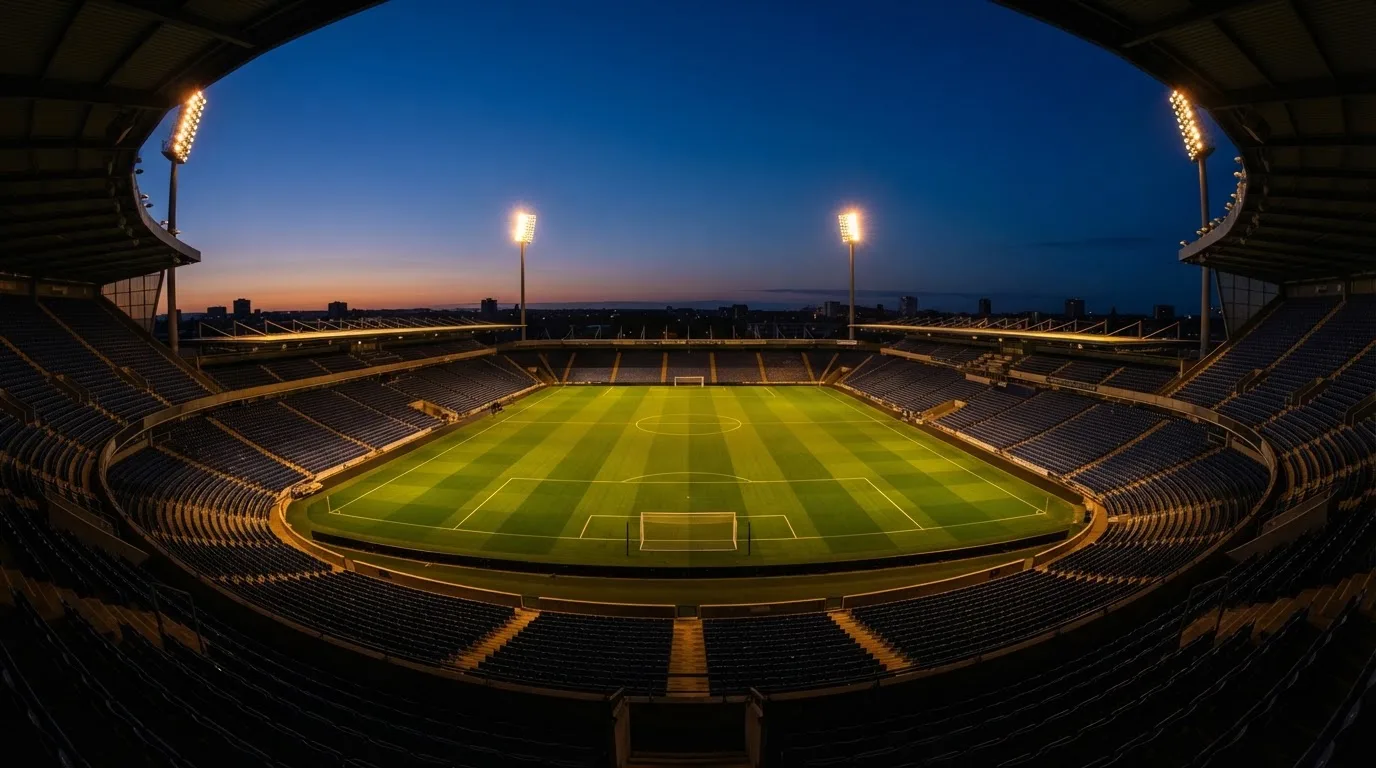 An empty football stadium with floodlight masts at dusk