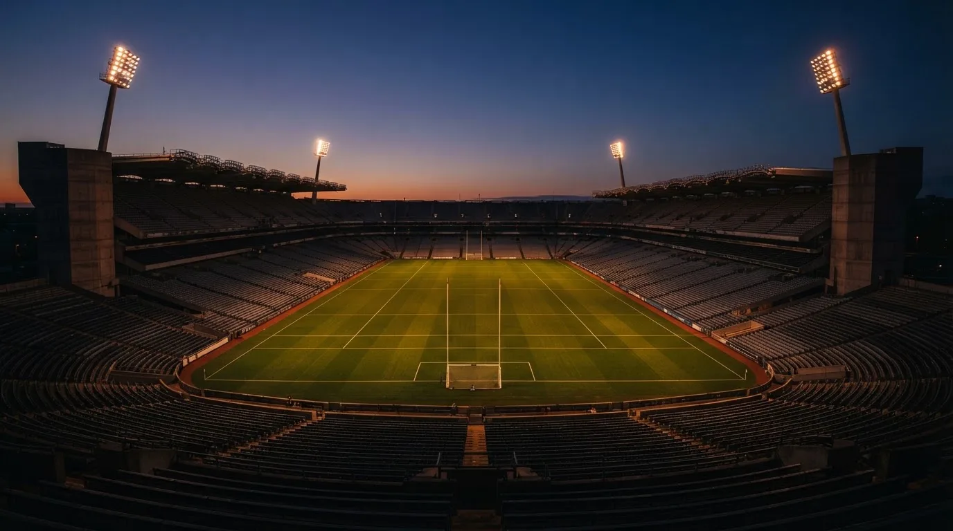 An empty football stadium with floodlight masts at dusk