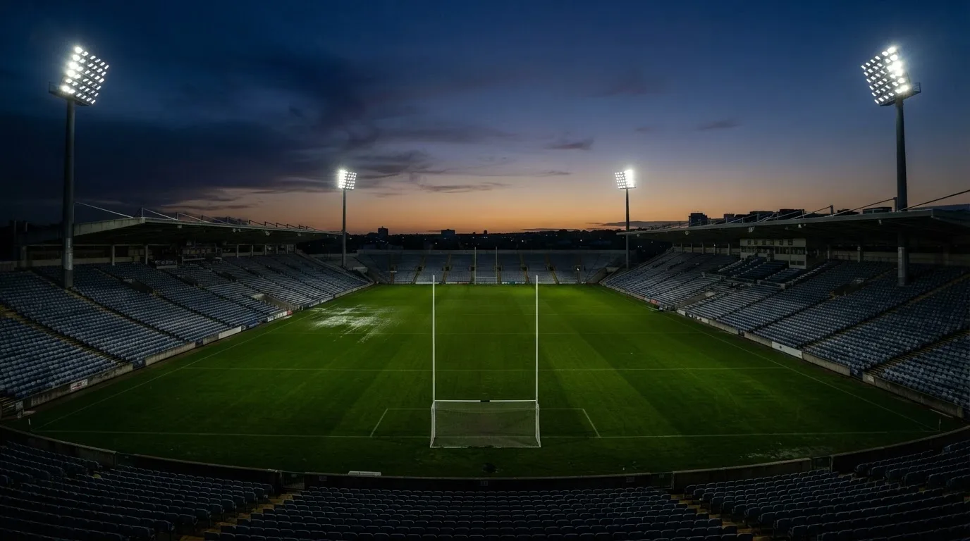 An empty football stadium with floodlight masts at dusk