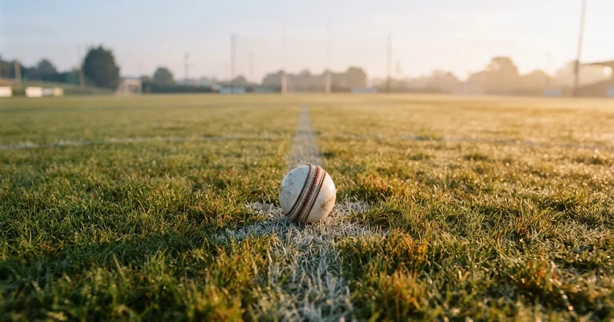 A ball on the centre spot of a grass pitch in morning light