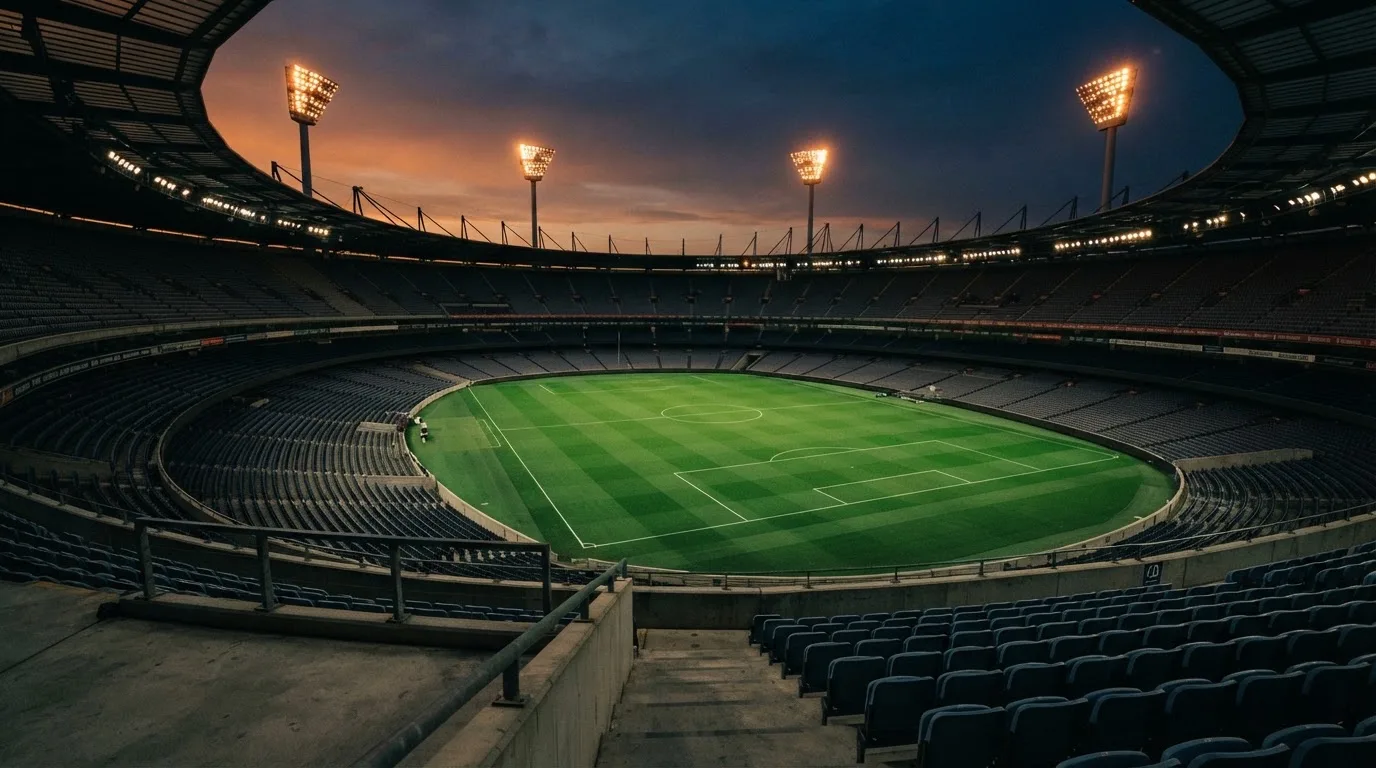 An empty football stadium with floodlight masts at dusk